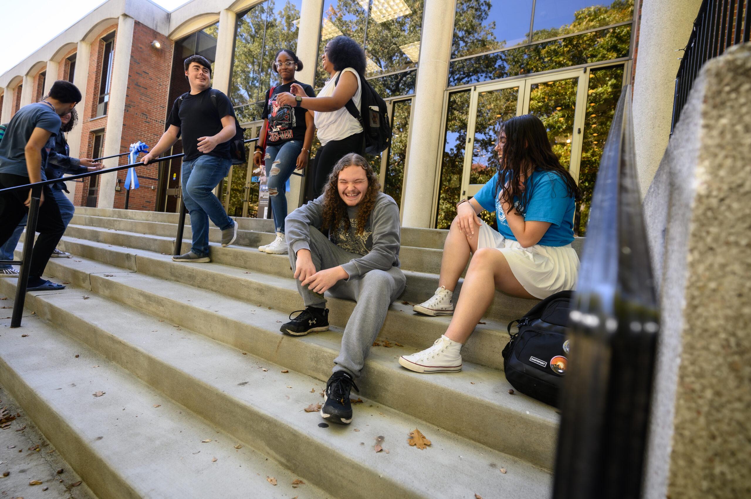 Group of diverse students smiling and huddled close together in semicircle