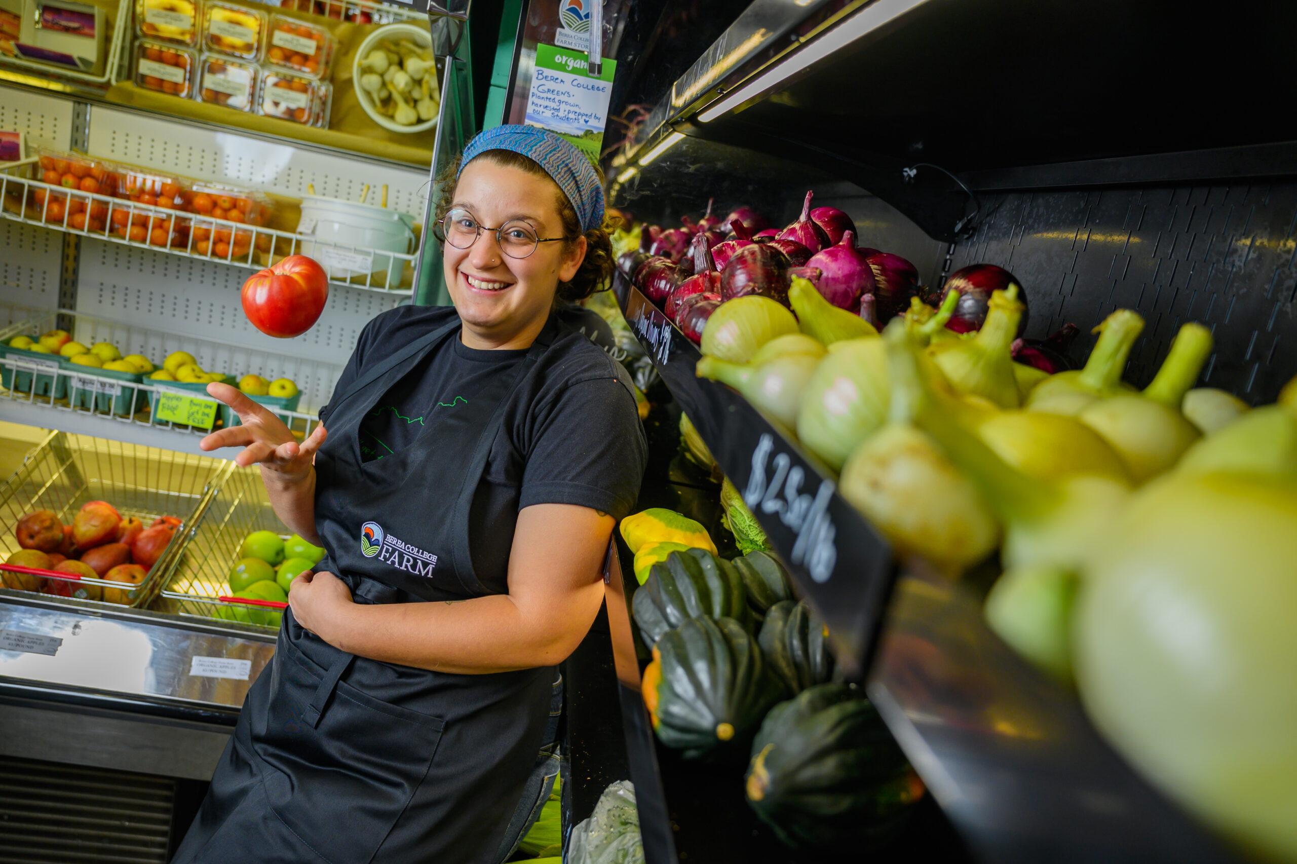 Person surrounded by produce at the Berea College Farm Store.