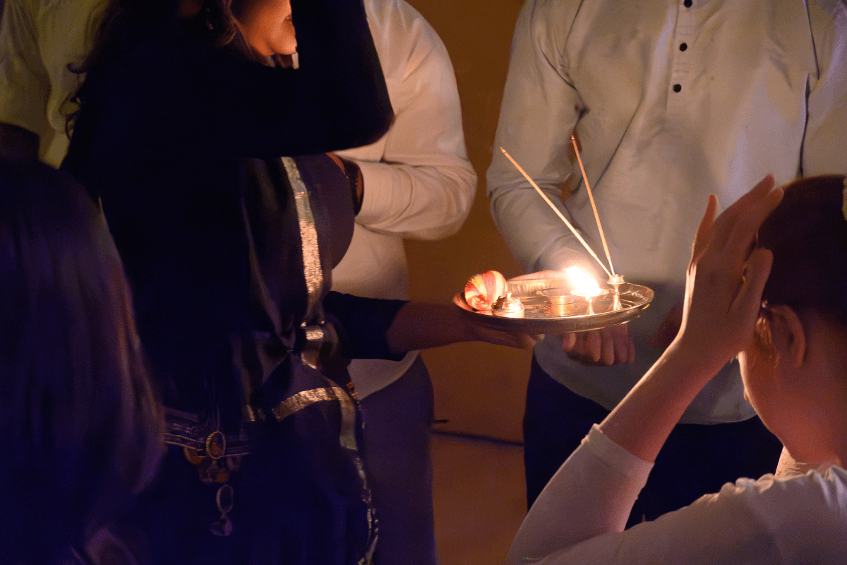Students celebrating Diwali by lighting a candle in a dimly lit room.