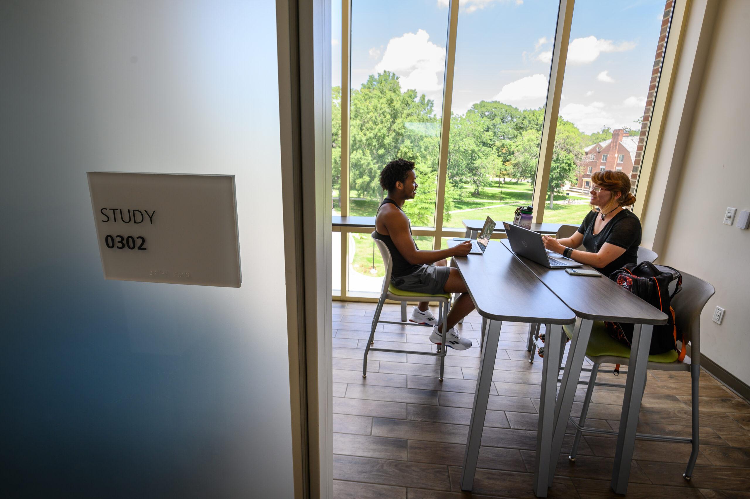 Two students chatting in a room labeled 'study room.'
